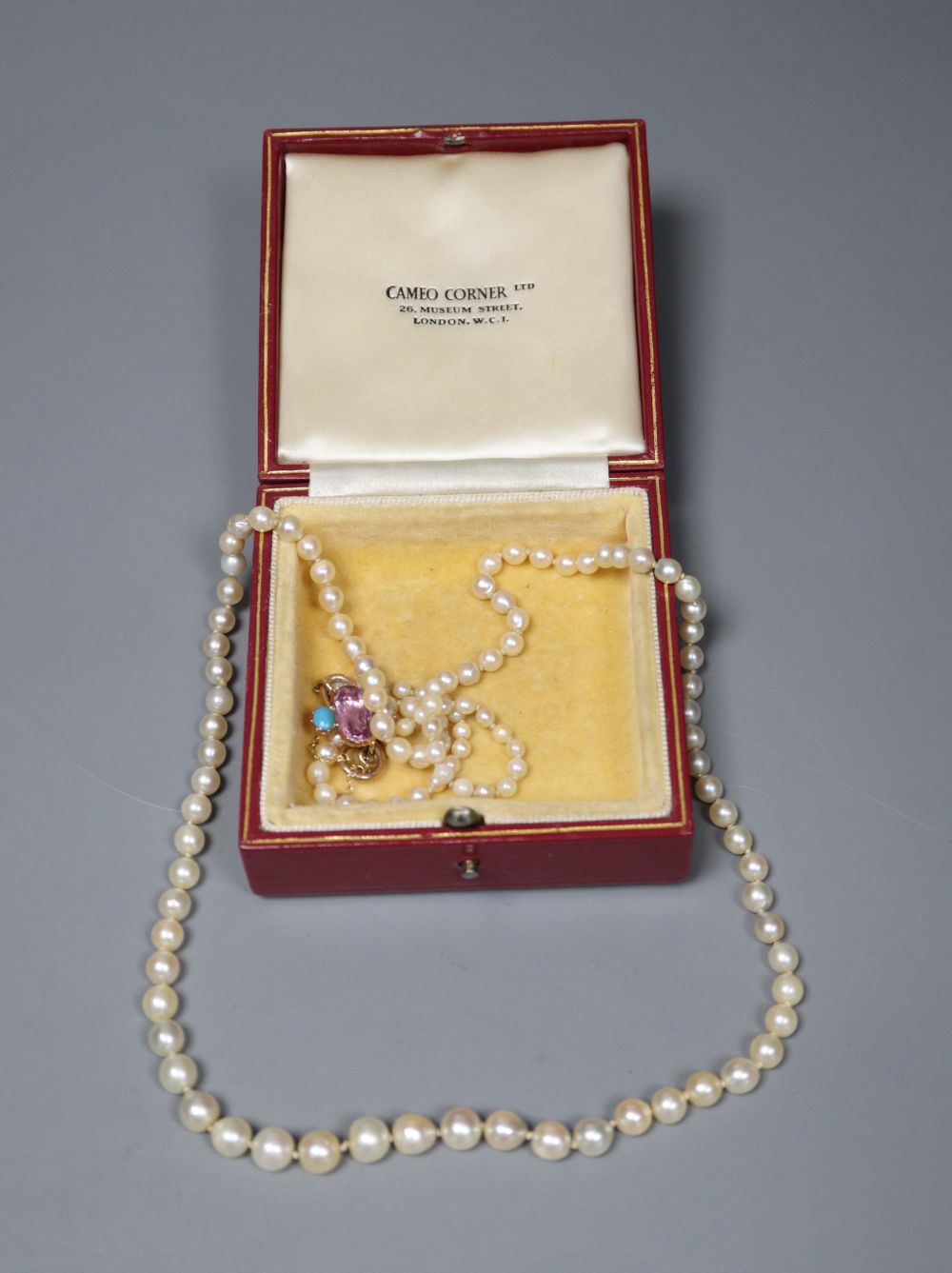 A single strand graduated cultured pearl necklace with yellow metal and gem set clasp (ex. ring head?), 74cm.